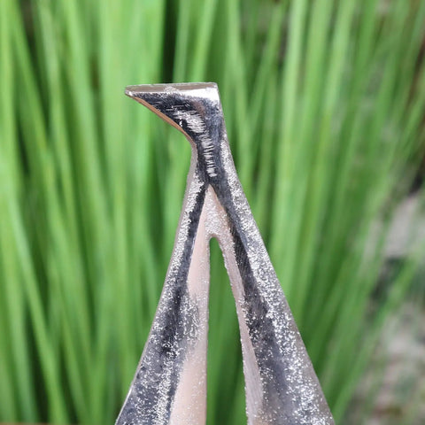 Silver metal nail clipper with sharp angled tip and textured surface shown with mandvi sailing boat ornament model