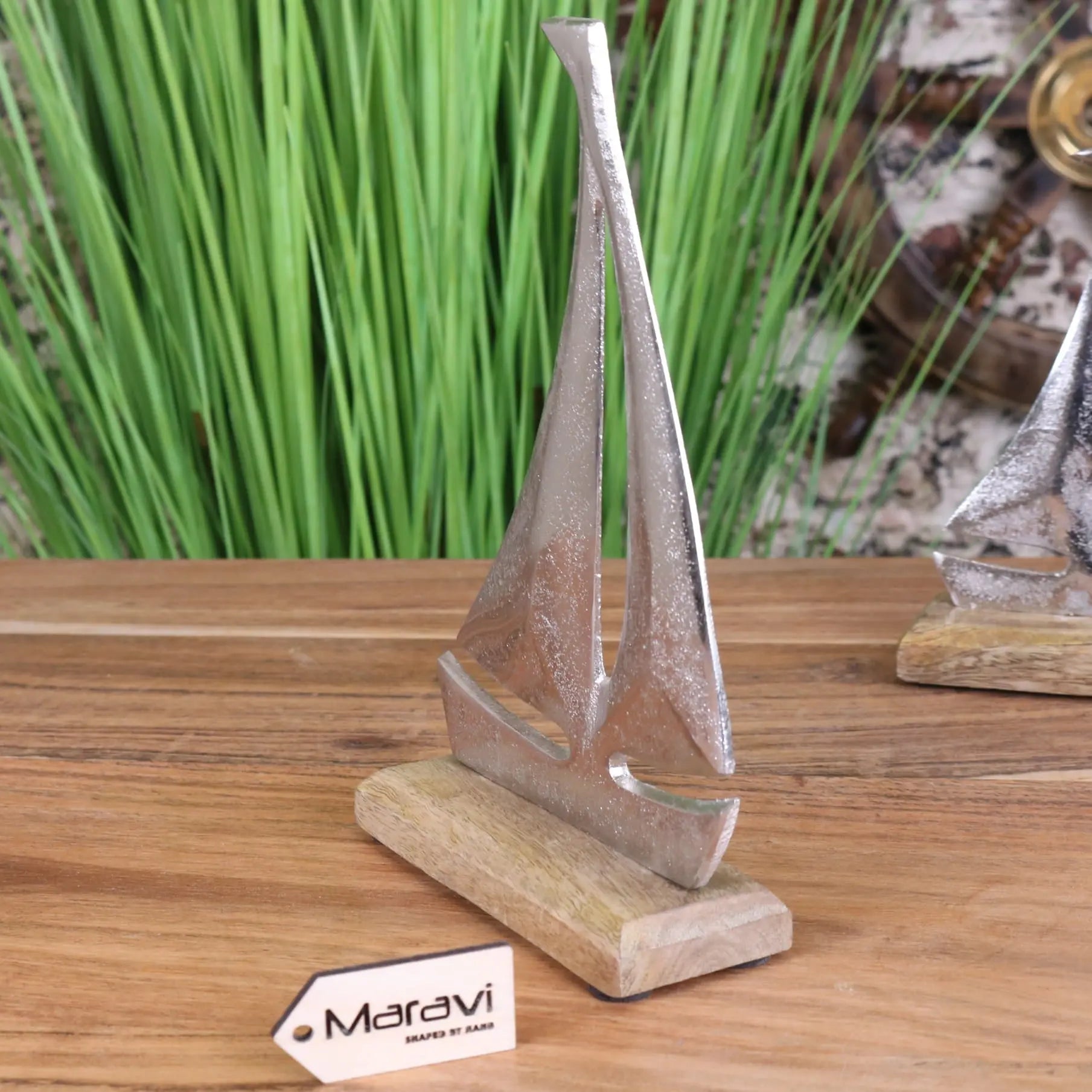 Silver-toned metal mandvi sailing boat ornament with textured finish on light wood base for home decor