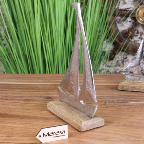 Silver-toned metal mandvi sailing boat ornament with textured finish on light wood base for home decor