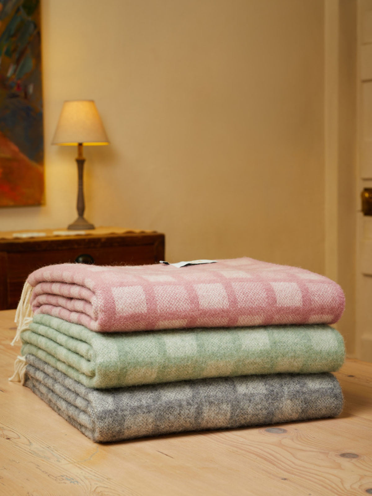 Stack of three manhattan pure new wool throws in pastel pink mint green and gray with intricate square checkered pattern