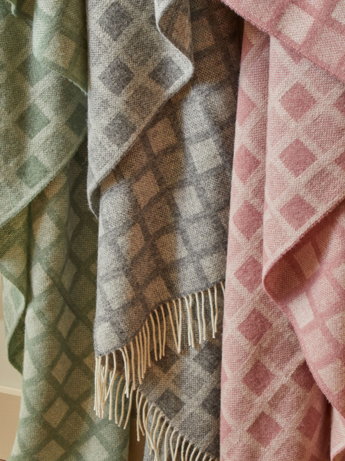 Three manhattan pure new wool throws in pastel green gray and pink with intricate square diamond patterns and fringe