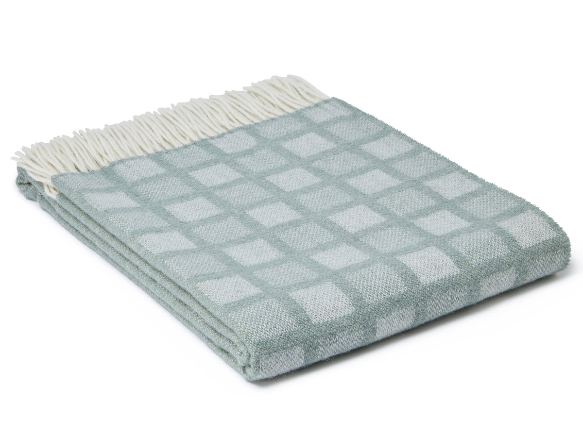 A soft light blue manhattan pure new wool throw with intricate square pattern and cream fringe edge inspired by manhattan skyline