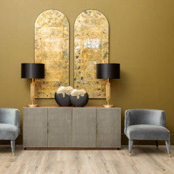 Gold leaf arched mirrors with black drum shade manor table lamps on a gray console table setup