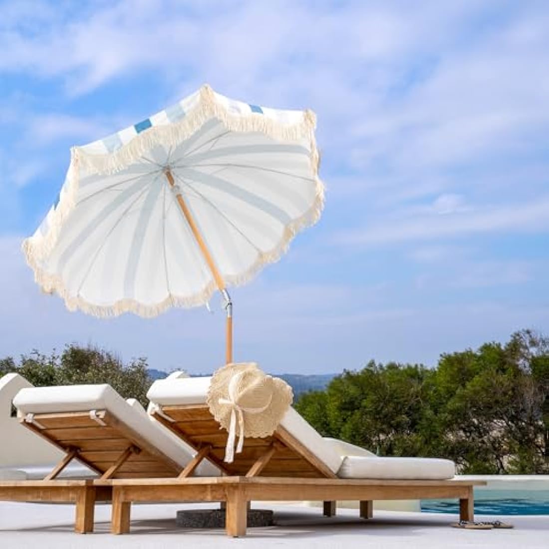 A white garden umbrella parasol with light blue stripes wooden pole and fringed edges for outdoor patio use