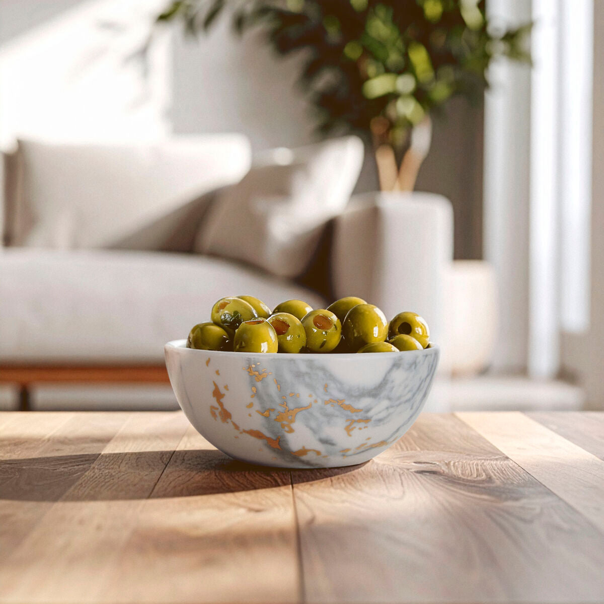 A white ceramic marble luxe snack bowl with gold accents filled with green olives perfect for serving snacks