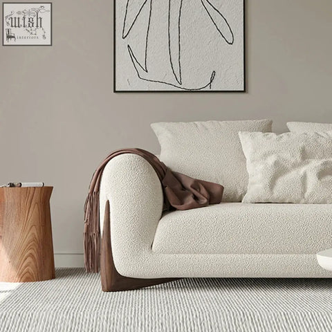 Cream-colored mariko sofa with plush sophistication textured fabric, deep cushioning, dark wood legs, and brown throw blanket