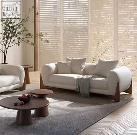Cream-colored mariko sofa with plush sophistication featuring deep cushioning rounded arms and wooden legs with green throw