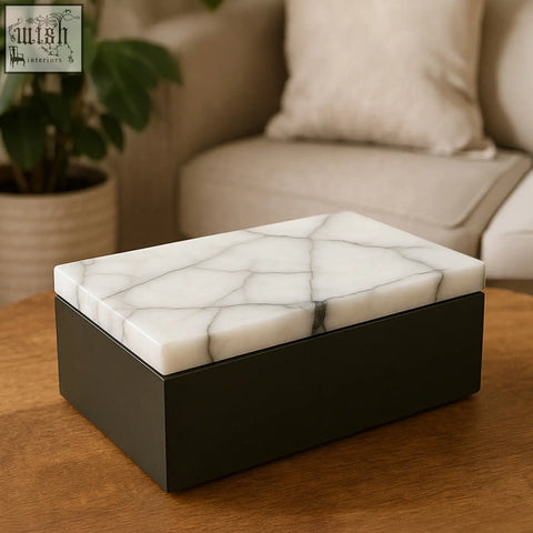 A small marble trinket box with a white marble top featuring gray veining and a matte black base