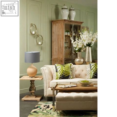 Beige tufted sofa with green and black throw pillows in a room featuring marmo marble effect large ceramic jar