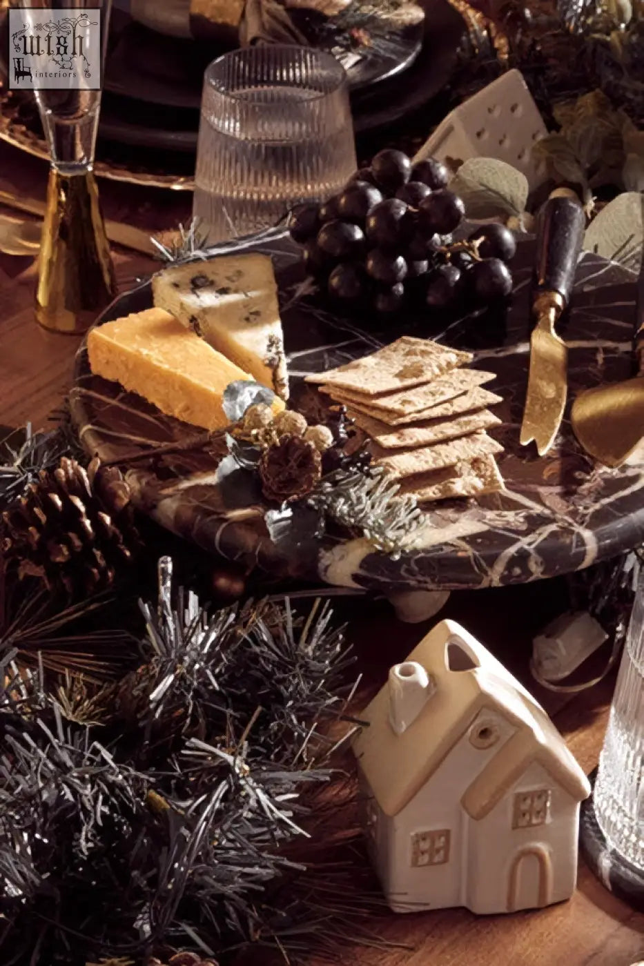 Cream-colored ceramic house figurine displayed alongside marmore black and gold marble cake stand for elegant cake presentation