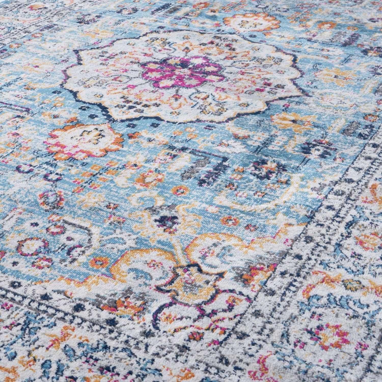 A marrakech vintage area rug with faded blue background and intricate floral geometric patterns in soft pastels