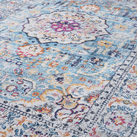 A marrakech vintage area rug with faded blue background and intricate floral geometric patterns in soft pastels