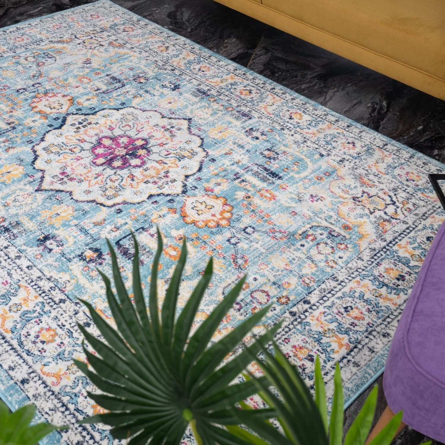 A marrakech vintage area rug with faded blue base and intricate floral geometric patterns in muted purples pinks and creams