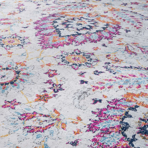 A vibrant marrakech vintage rug with a distressed white base and intricate pink orange teal and navy floral patterns