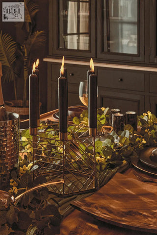 Black taper candles with gold bases in a gold geometric hexagonal candle holder for stylish decor