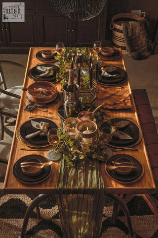 Elegant wooden dining table set with dark plates gold cutlery and a green runner featuring martina hexagonal candle holder