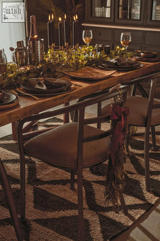 Rustic wooden dining table with dark metal legs featuring a martina hexagonal candle holder with greenery