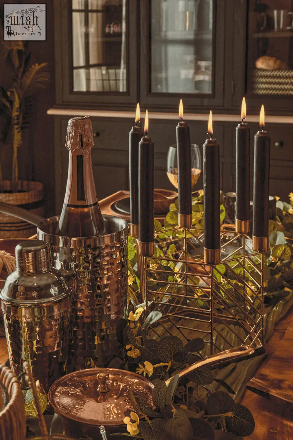 A sleek hammered copper cocktail shaker with a polished finish shown alongside a Martina hexagonal candle holder