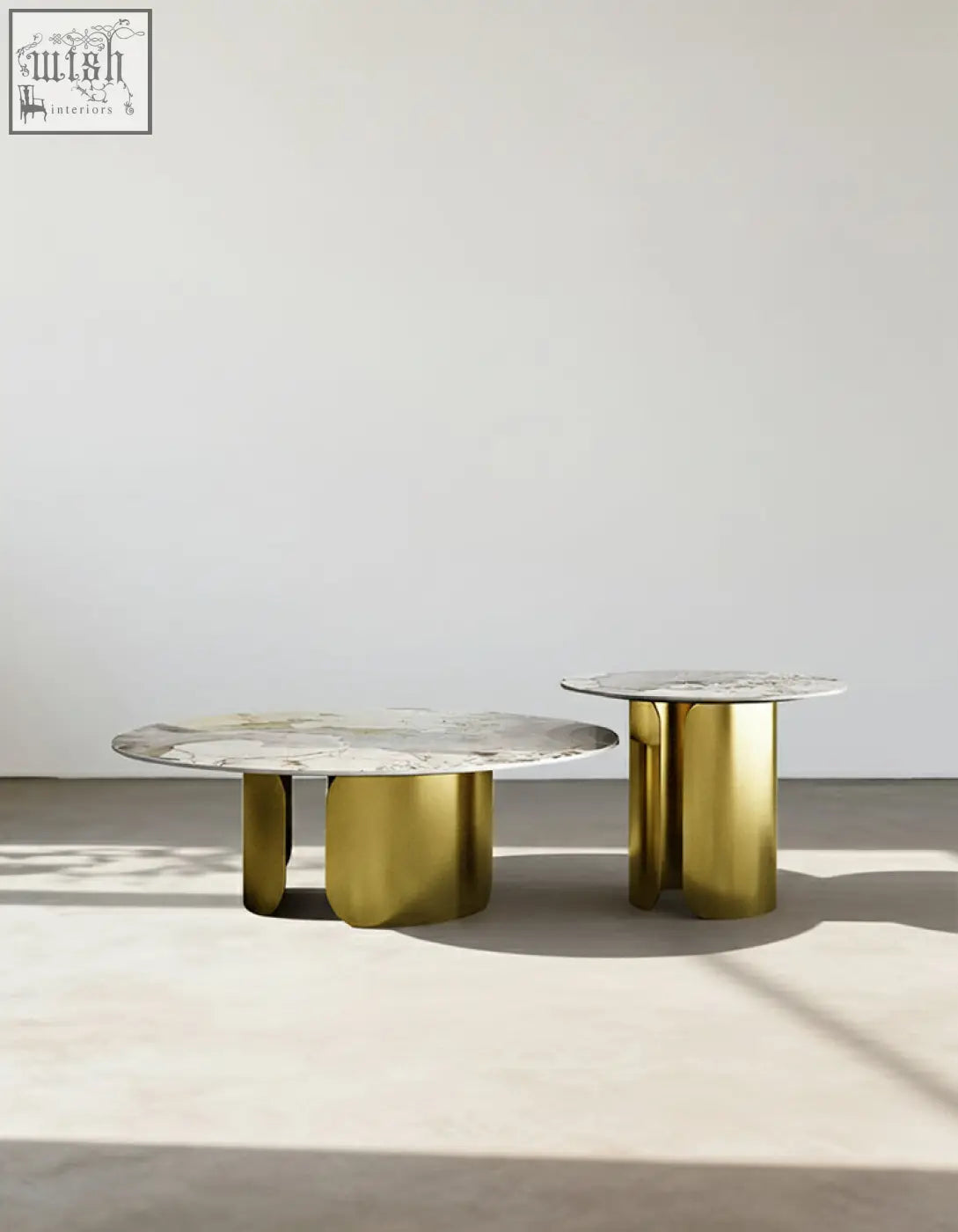 Two minimalist nesting coffee tables with white sintered stone tops and polished gold cylindrical legs from maru set