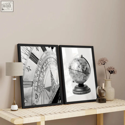 Two black-framed masculine wall art prints featuring a vintage sundial and antique globe on a woven table