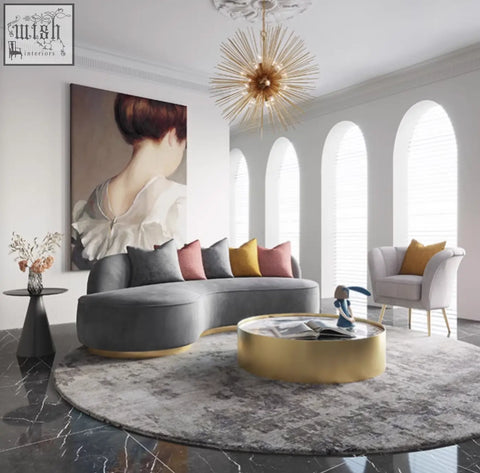 Gray velvet sectional sofa with gold trim and colorful pillows paired with a marble coffee table set