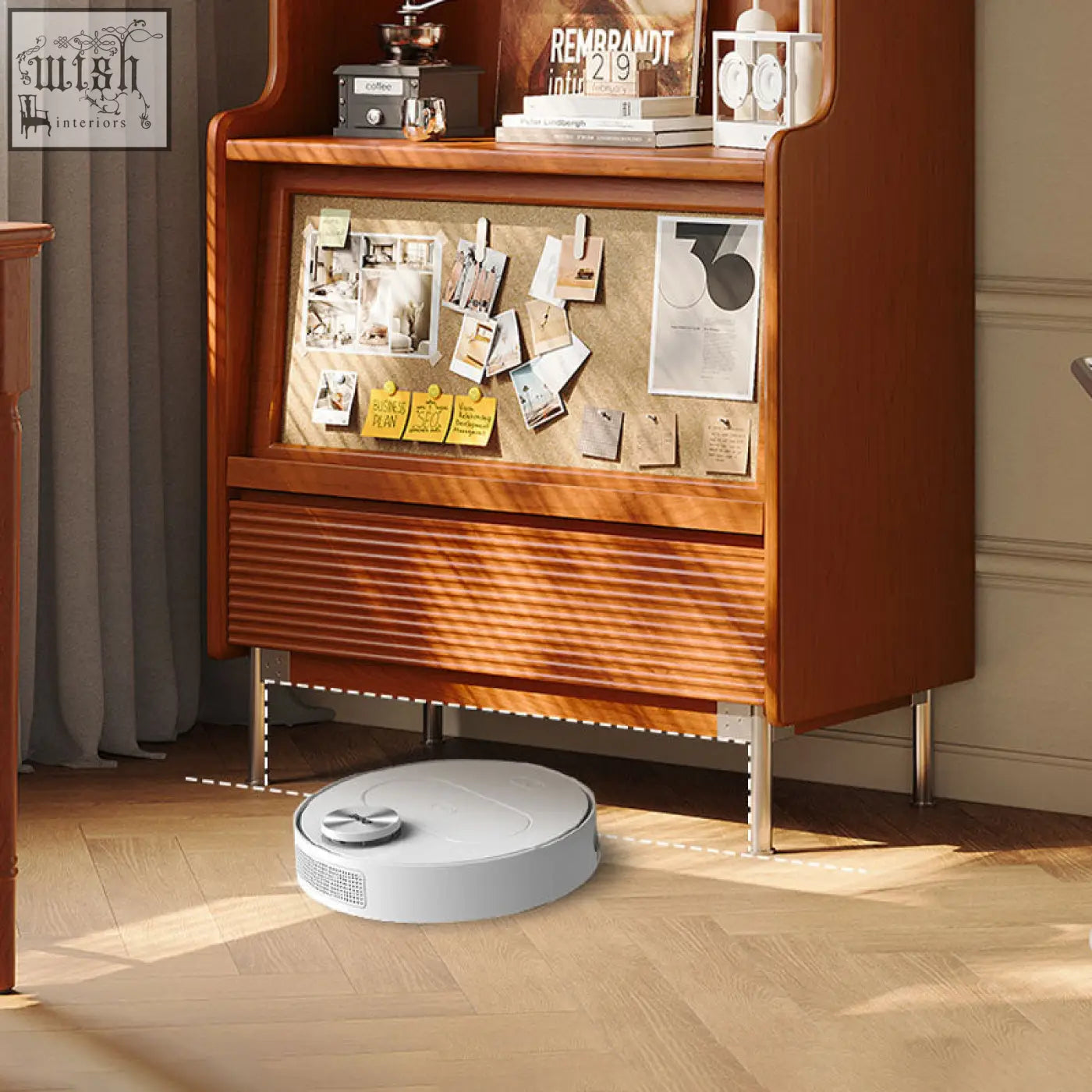 White circular robotic vacuum cleaner with silver button next to cherry wood mason tall sideboard with bookcase