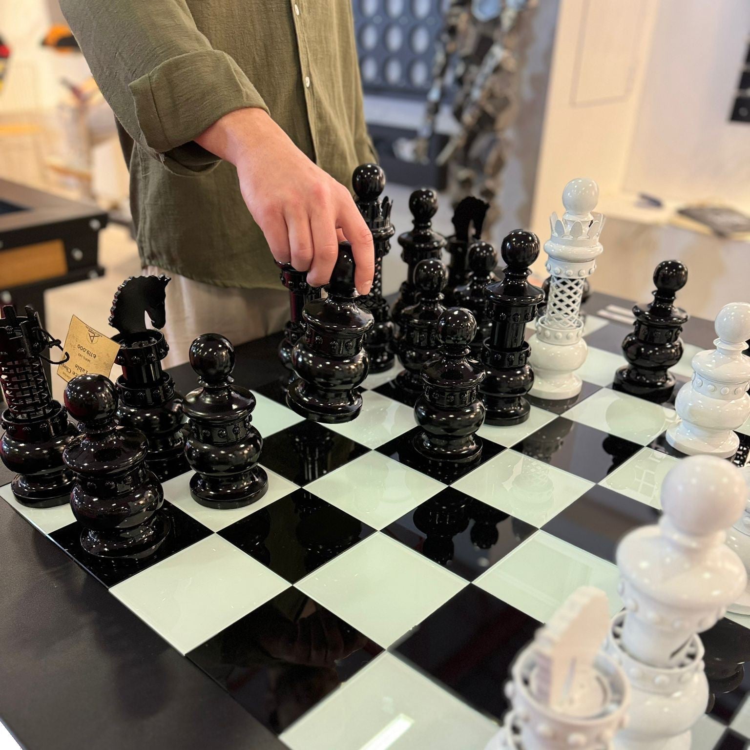 Glossy black and white ornate chess pieces on a reflective archtwain masterpiece chess table checkered board
