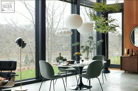 Modern white spherical pendant lights hang above the masuda oval dining table with marble top for stylish oval dining