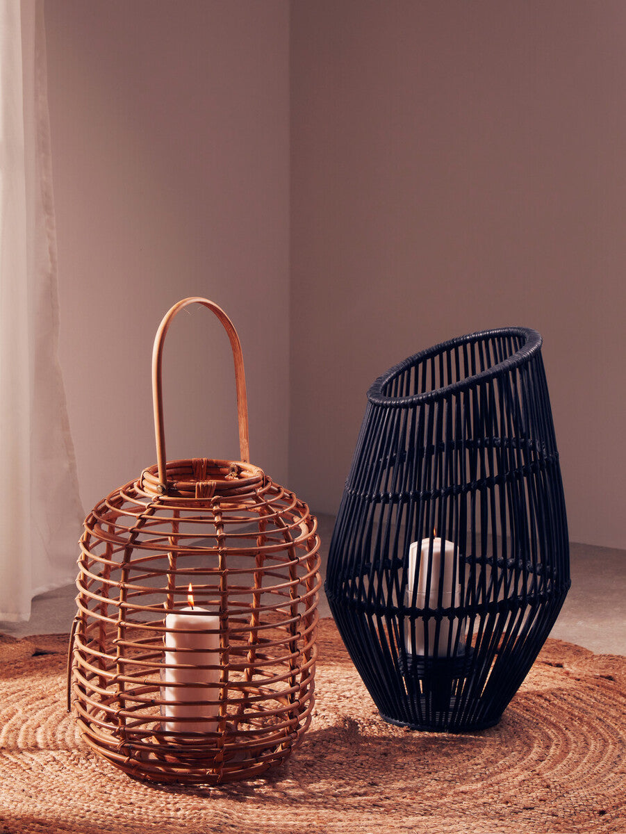 Mataram tall natural rattan lantern with a white candle inside next to a sleek black wicker lantern