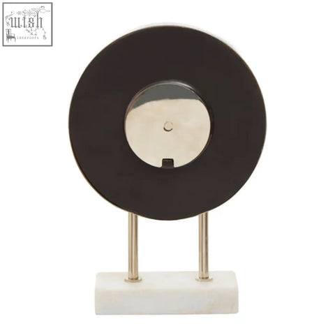 Black vinyl record clock with silver center and chrome legs on a white marble base featuring a sleek marble base design