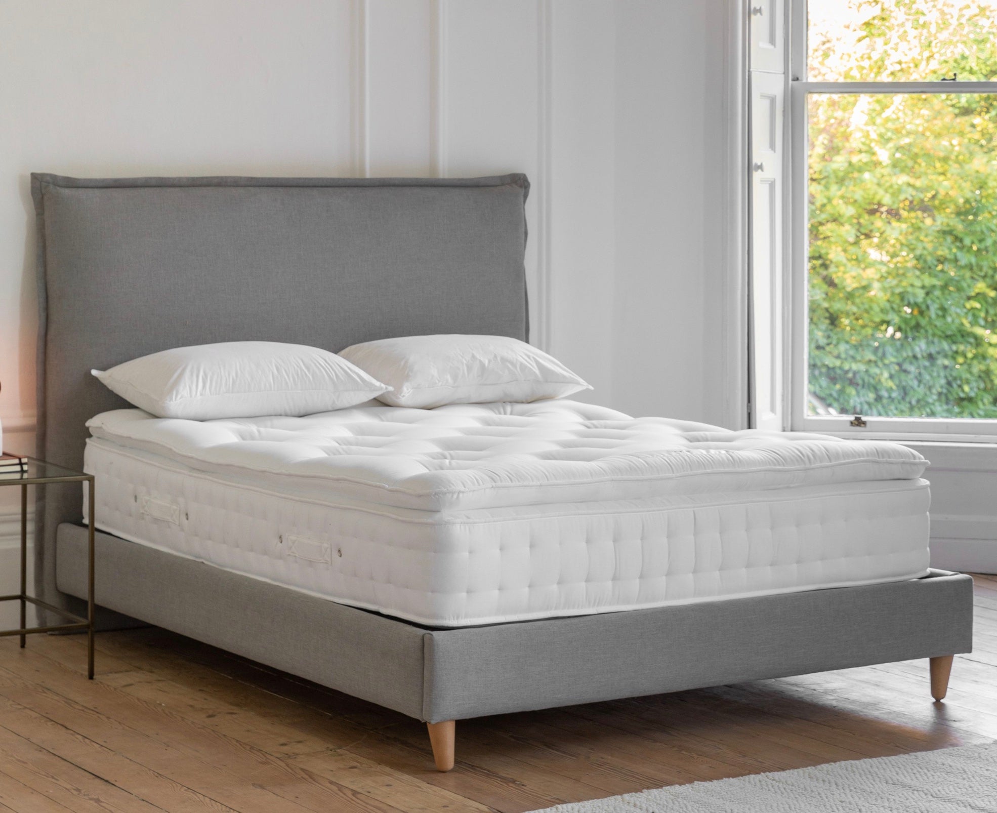 Gray upholstered double bed with luxury pillow top mattress and matching white quilted pillows