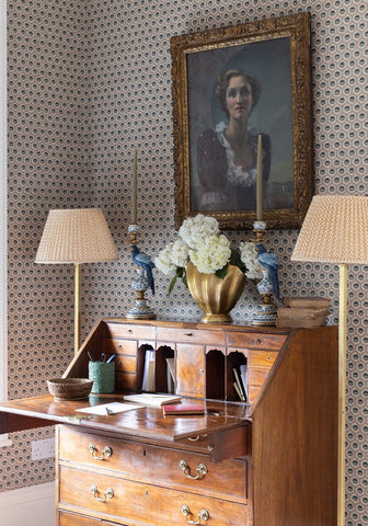 Antique wooden writing desk with brass hardware and a gold-toned vase holding white hydrangeas in classic brown