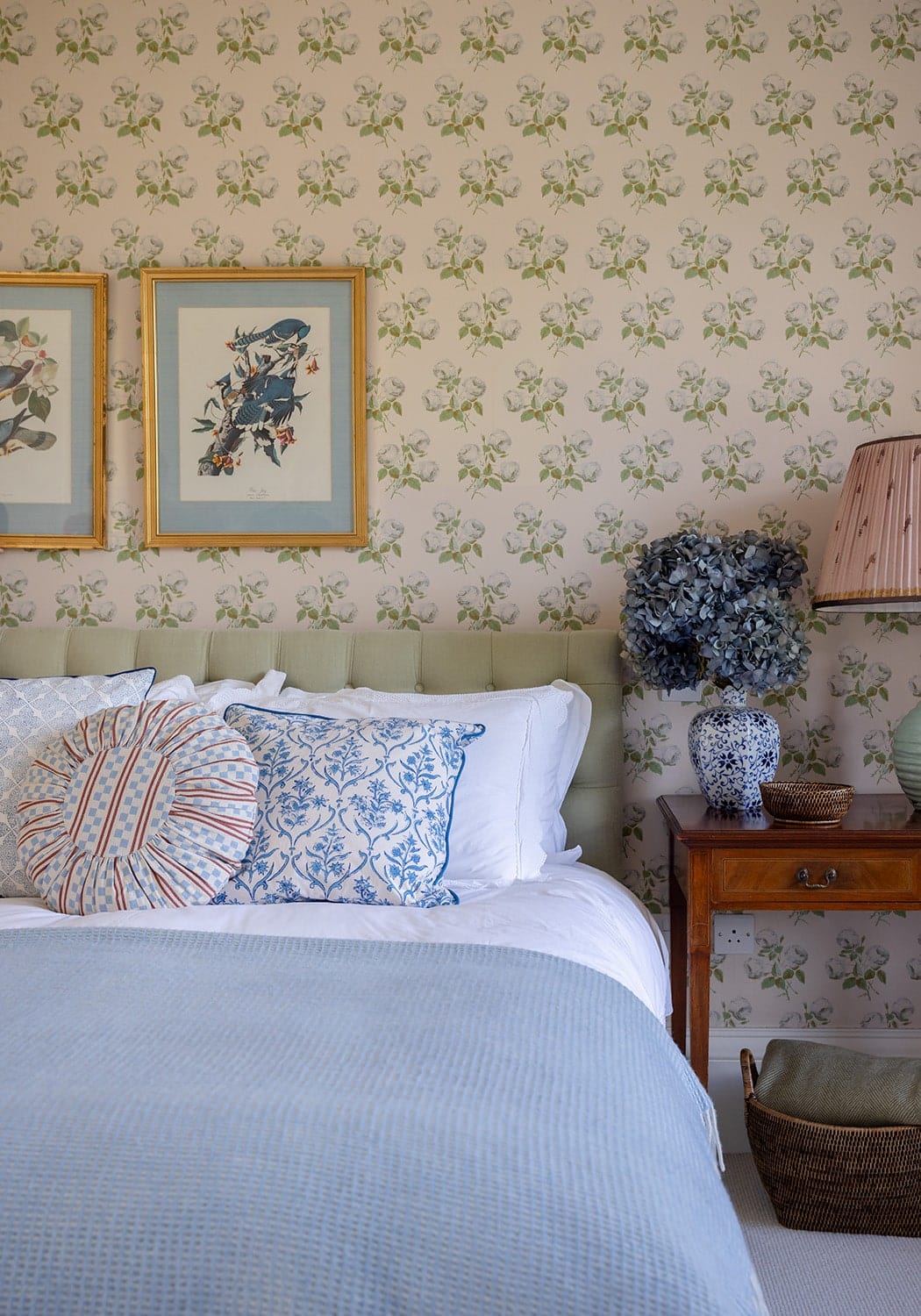 A blue and white embroidered throw pillow resting on a bed with a classic brown mayfair tray holdall
