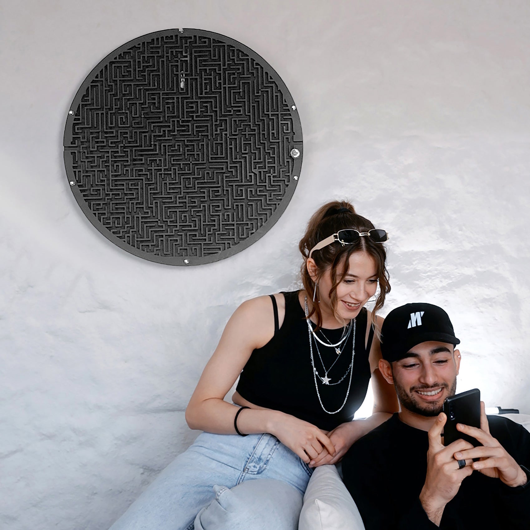 Black circular maze board wall game with metallic finish featuring target area and ball holder for fun play