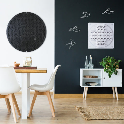 Black circular maze board wall game with textured surface and metallic fasteners featuring target area and ball holder