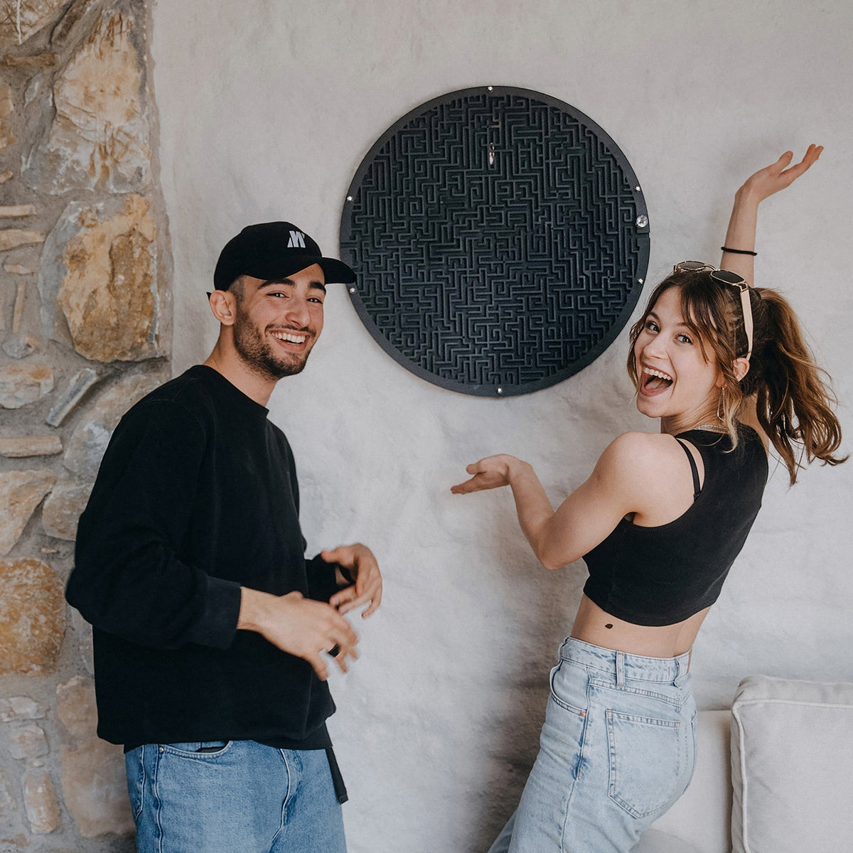 Black circular wall game maze board with textured labyrinth and metallic edge hardware with target area and ball holder