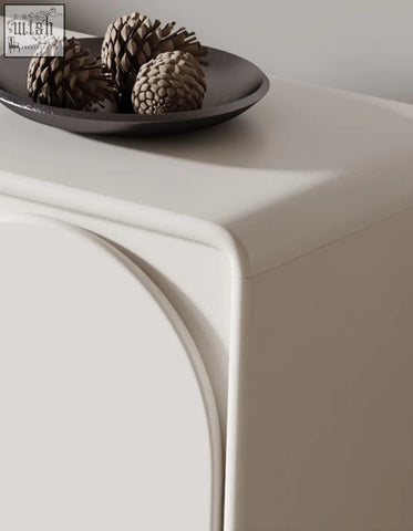 Dark gray ceramic plate with three brown pinecones on a cream mediterranean style sideboard for decor