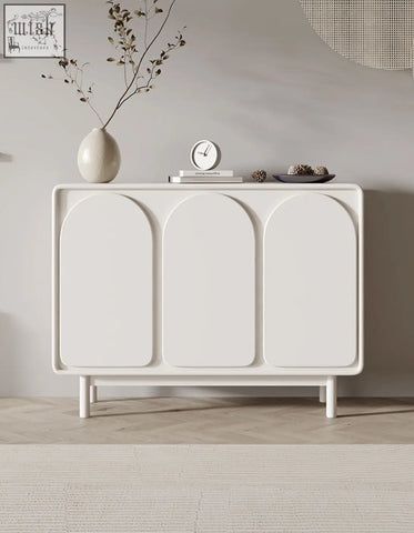 White mediterranean style sideboard with three arched cream doors and slender legs in a minimalist design