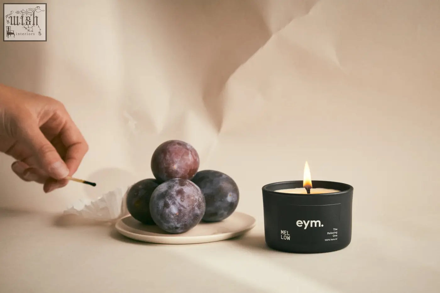 Black cylindrical mini candle with mellow label and eym branding lit flame inside for a cozy vibe