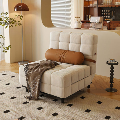 Beige striped tufted corduroy sofa bed with brown cylindrical pillow and patterned throw blanket draped over it