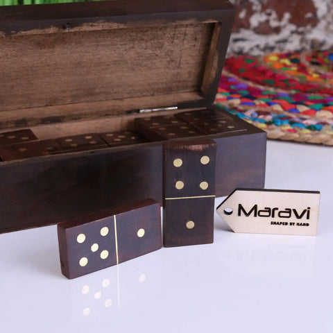 Dark wooden domino set with gold dots neatly arranged beside a mera wooden domino carved storage box and tag