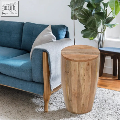 A rustic light brown merlin mango wooden drum side table with natural wood grain and tapered cylindrical shape