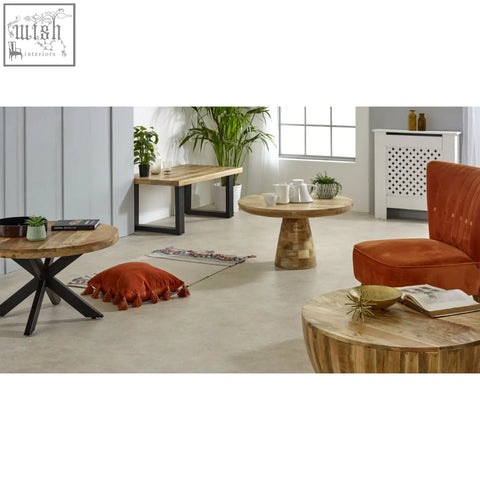 Rust-colored velvet armchair with tufted back next to merlin mango wooden round coffee table mushroom style round coffee