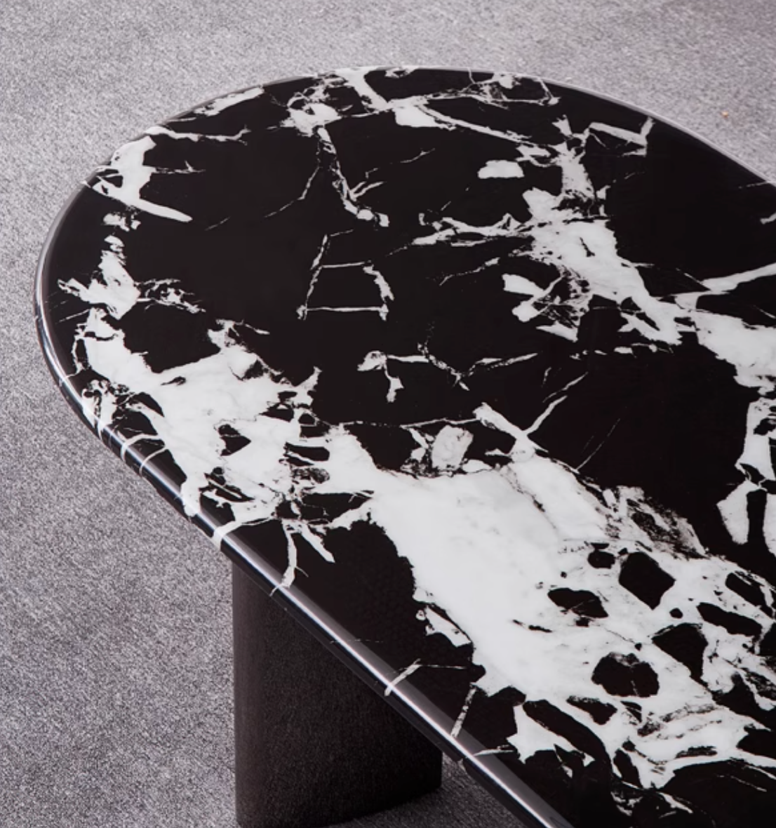 Black and white marble meroy dining table with a sleek oval top and minimalist pedestal base for modern dining