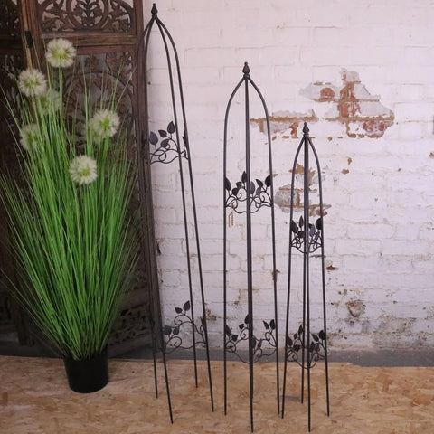 Three black metal garden obelisks with leaf and vine designs in varying heights for garden decor