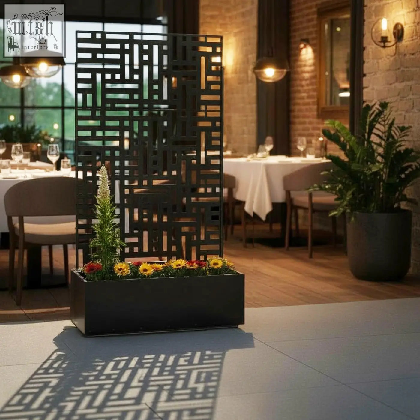 Black metal indoor outdoor privacy screen with geometric design and integrated planter box filled with colorful flowers