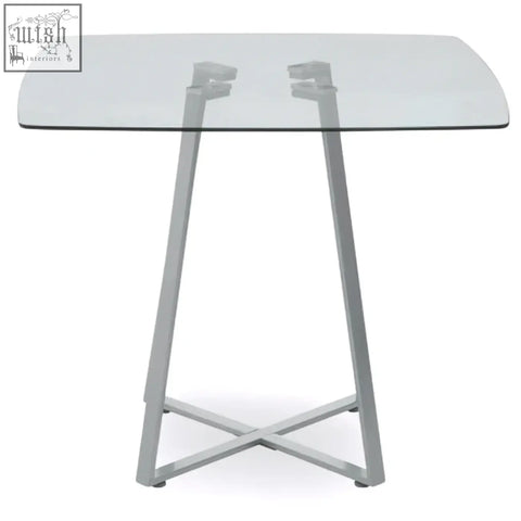 Modern minimalist metropolitan square matte grey dining table with clear glass top and silver x-shaped metal legs