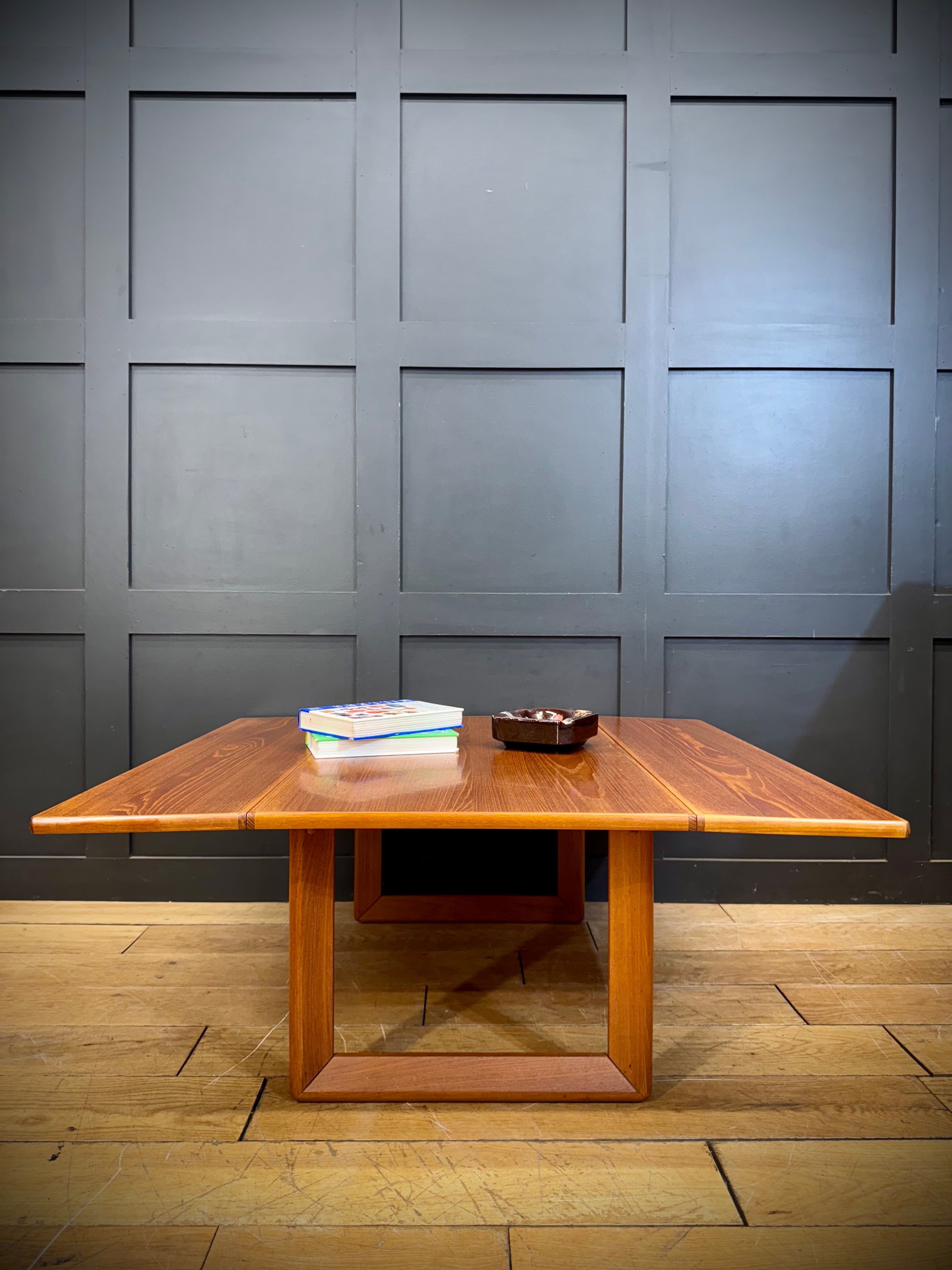 A warm-toned mid century teak drop leaf coffee table with sleek modern design and visible wood grain