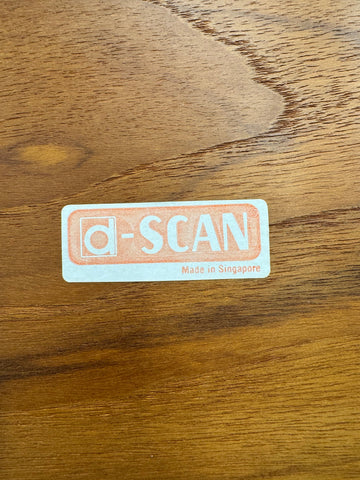 Rectangular light blue sticker with peach text d-scan made in singapore on a mid century teak drop leaf coffee table