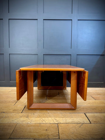 A mid-century modern teak drop leaf coffee table with warm polished wood and clean geometric lines
